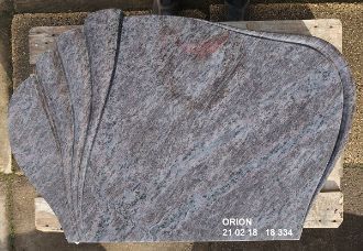 Graue Steinplatten in verschiedenen Formen auf einem Holzuntergrund.