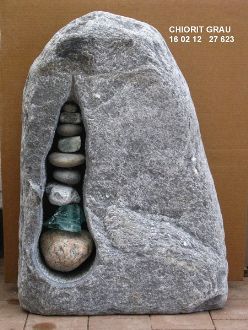 Eine graue Steinskulptur mit geschichteten Steinen im Inneren.