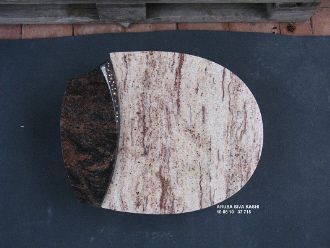 Halbrunder, zweifarbiger Stein mit glatter Oberfläche, helle und dunkle Maserung, auf schwarzem Untergrund