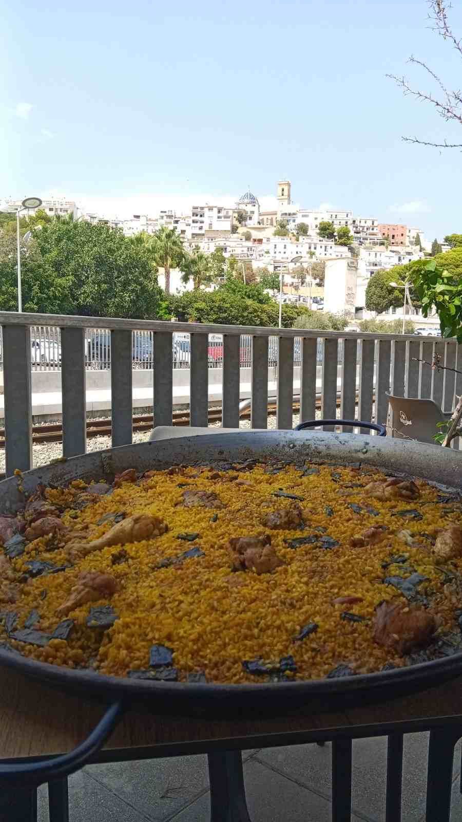 Bandeja de flores amarillas en un balcón, con vistas a la ciudad al fondo