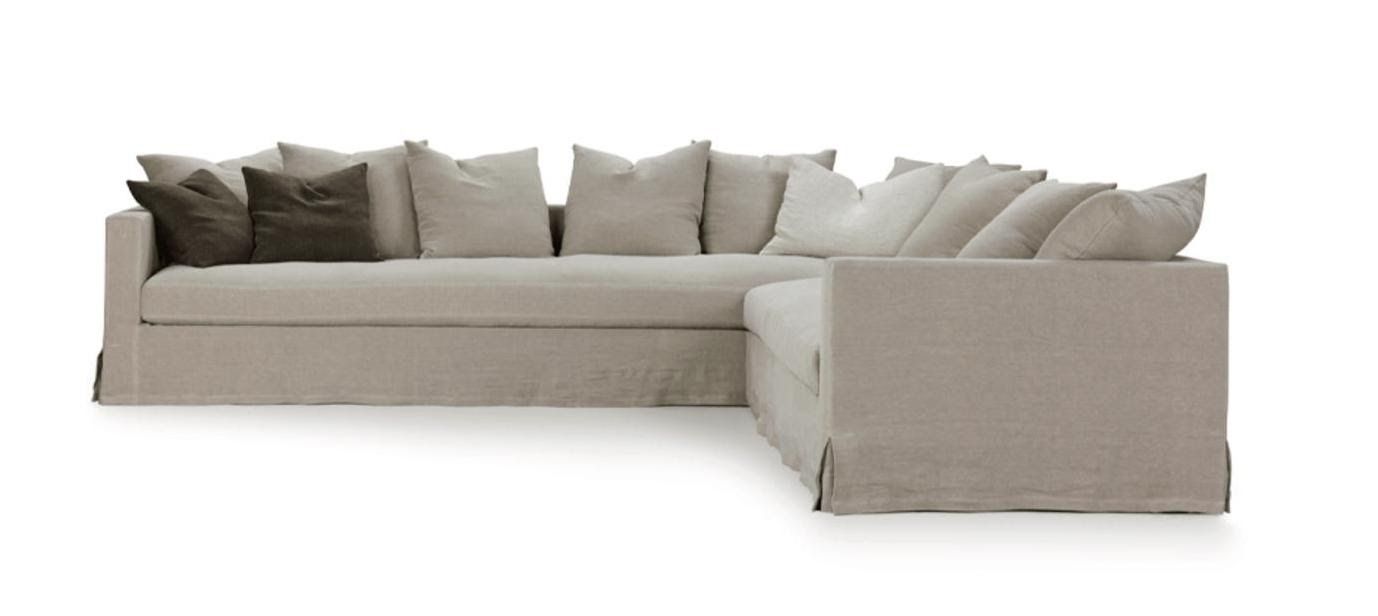 Sofá seccional beige con muchos cojines grandes y esponjosos.