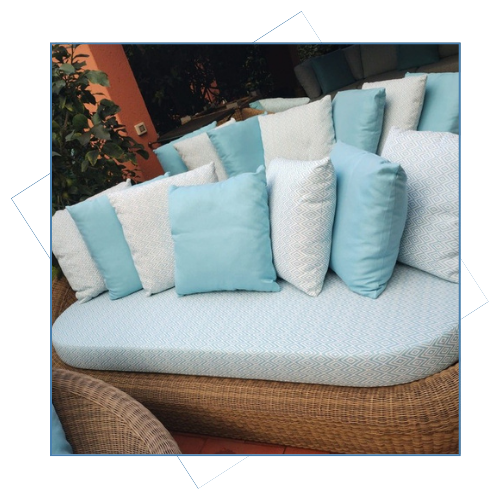 Un sofá de mimbre con almohadas azules y blancas.
