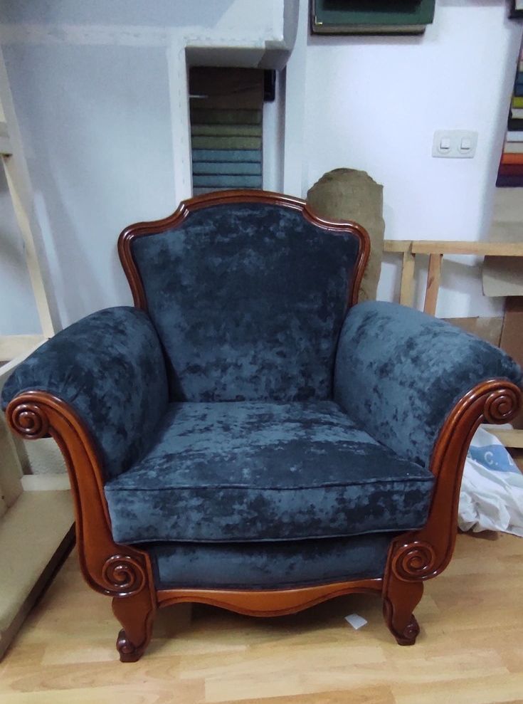 Una silla azul con marco de madera está sentada sobre un piso de madera.