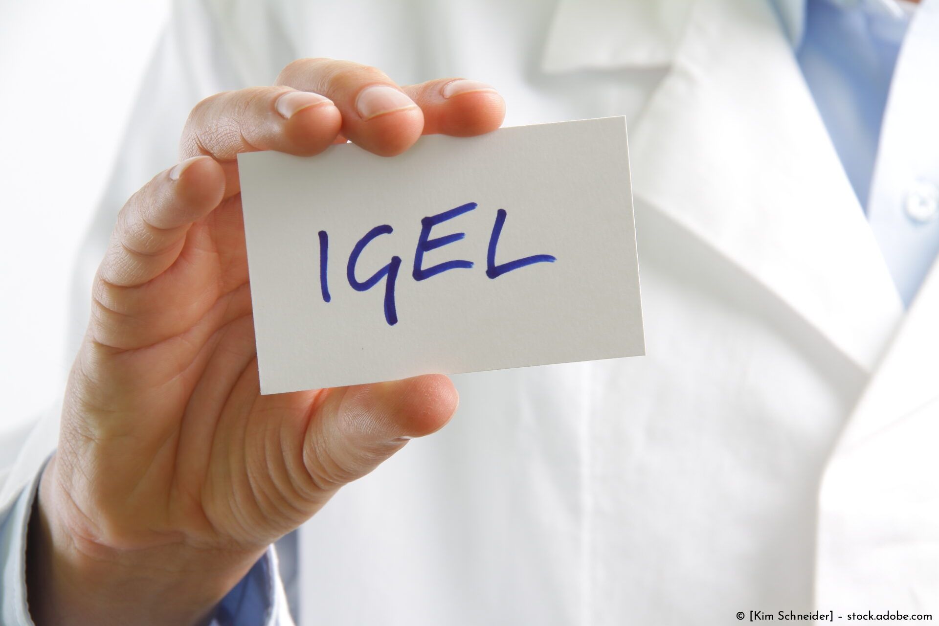 Eine Hand hält eine Karte mit der blauen Aufschrift „IGEL“, im Hintergrund ist ein weißer Laborkittel zu sehen.