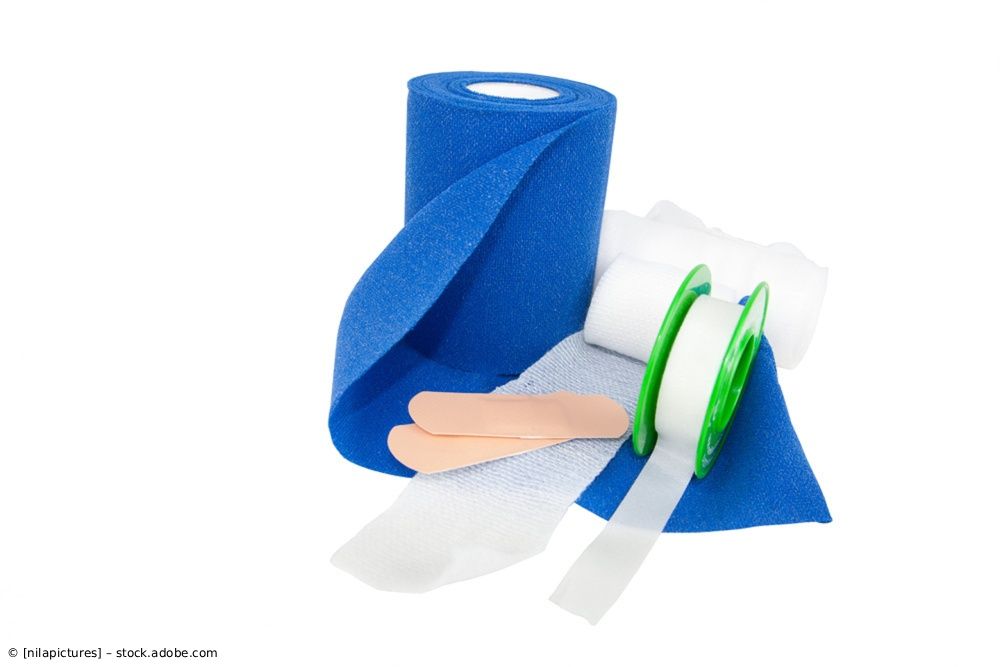 Blaue elastische Binde, Gaze und grüne Schere auf weißem Hintergrund