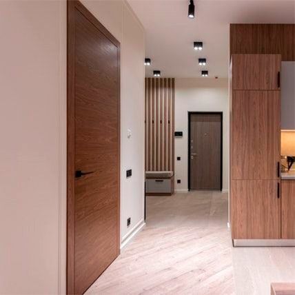 Pasillo interior con puertas de madera, armarios empotrados e iluminación de riel.