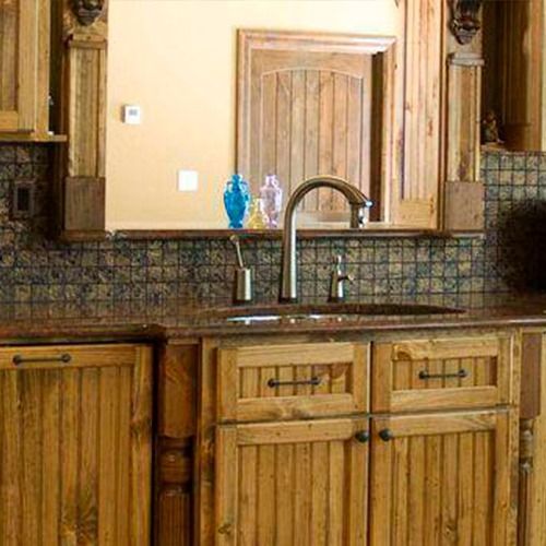 Cocina rústica con gabinetes de madera, grifo de cobre, protector contra salpicaduras marrón y fregadero.