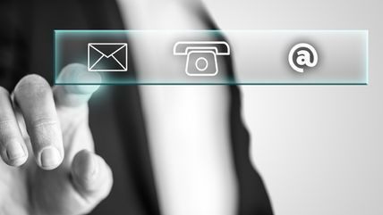 Una persona está presionando un botón con un teléfono, correo electrónico y íconos @.