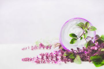 Hay un tazón de crema y flores en la mesa.