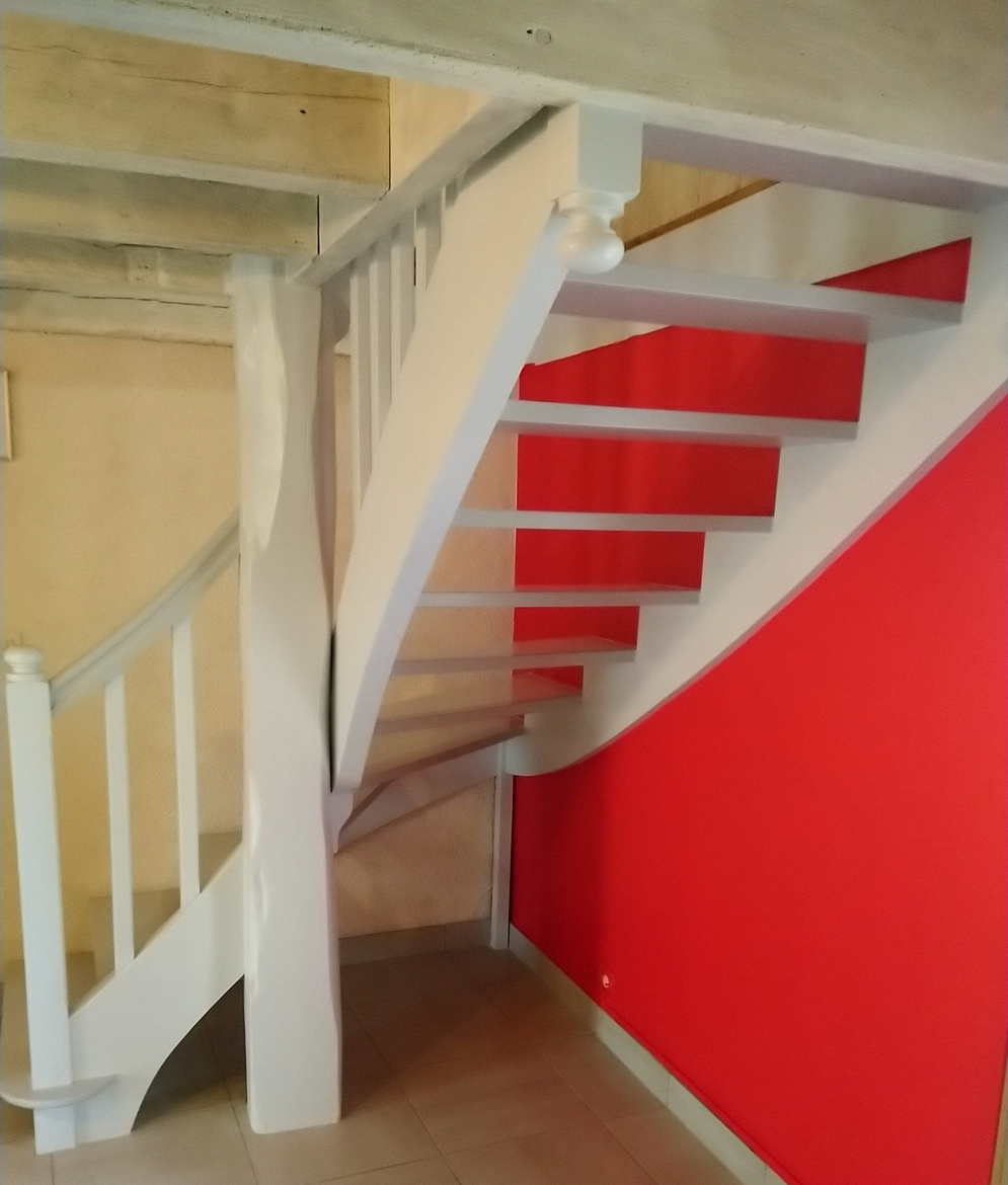 Escalier intérieur avec des rampes blanches, des marches blanches et un mur rouge vif en dessous
