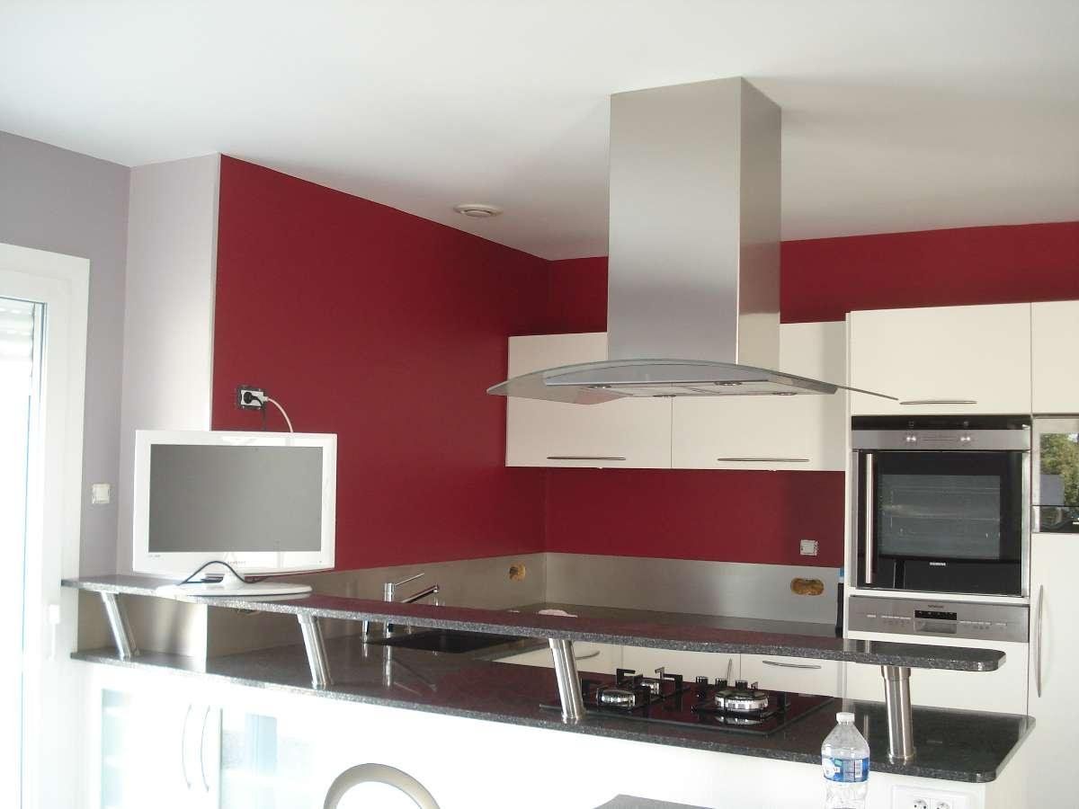 Cuisine moderne avec des murs rouges, des meubles blancs, une hotte en acier inoxydable et un plan de travail noir