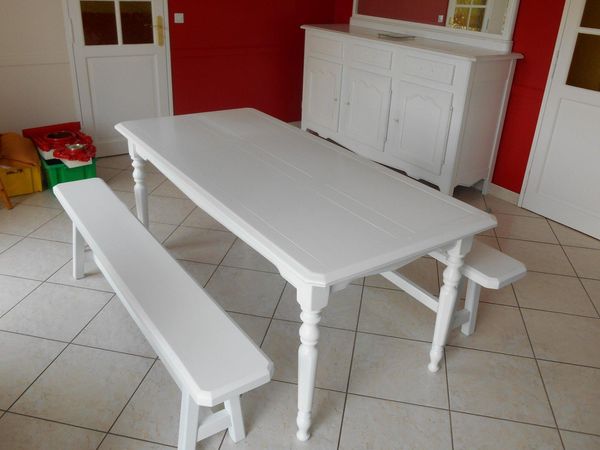 Table et banc blancs dans une pièce lumineuse avec des murs rouges et un sol carrelé