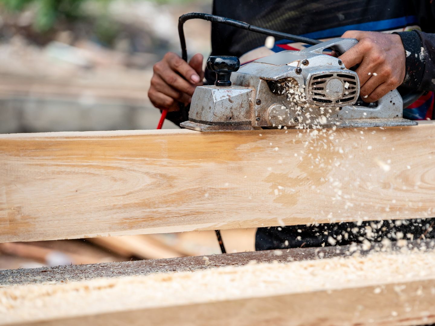 Une personne utilise une scie circulaire pour couper une planche de bois.