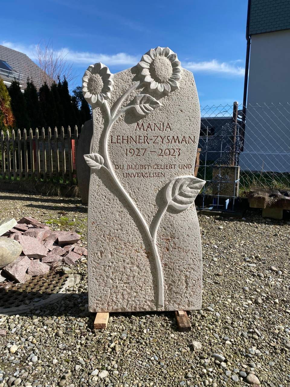 Dekorativer Grabstein aus Stein mit eingravierten Sonnenblumen auf einem sonnigen Friedhof oder in einem Garten