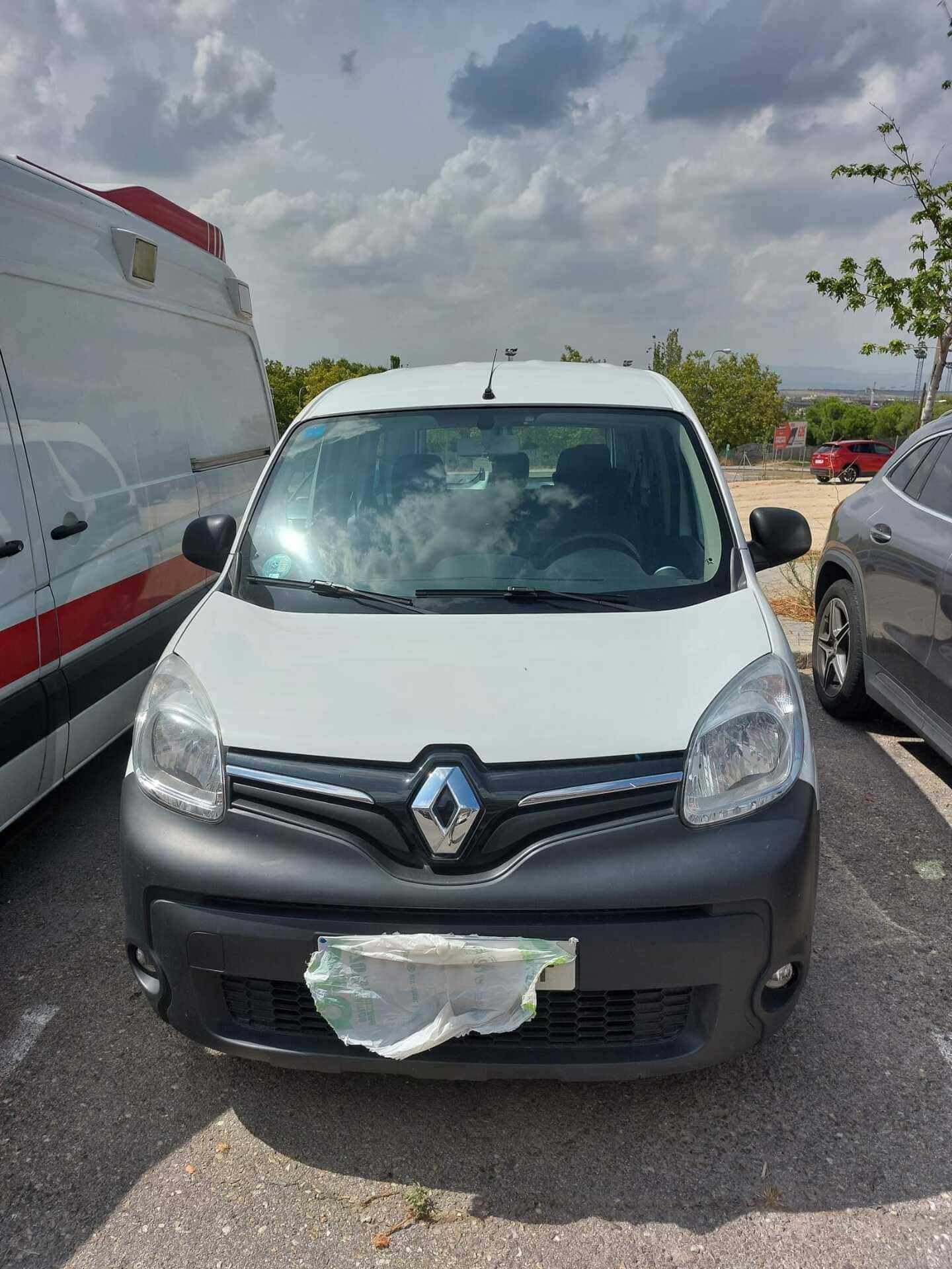 Un Renault Kangoo blanco está estacionado en un estacionamiento.