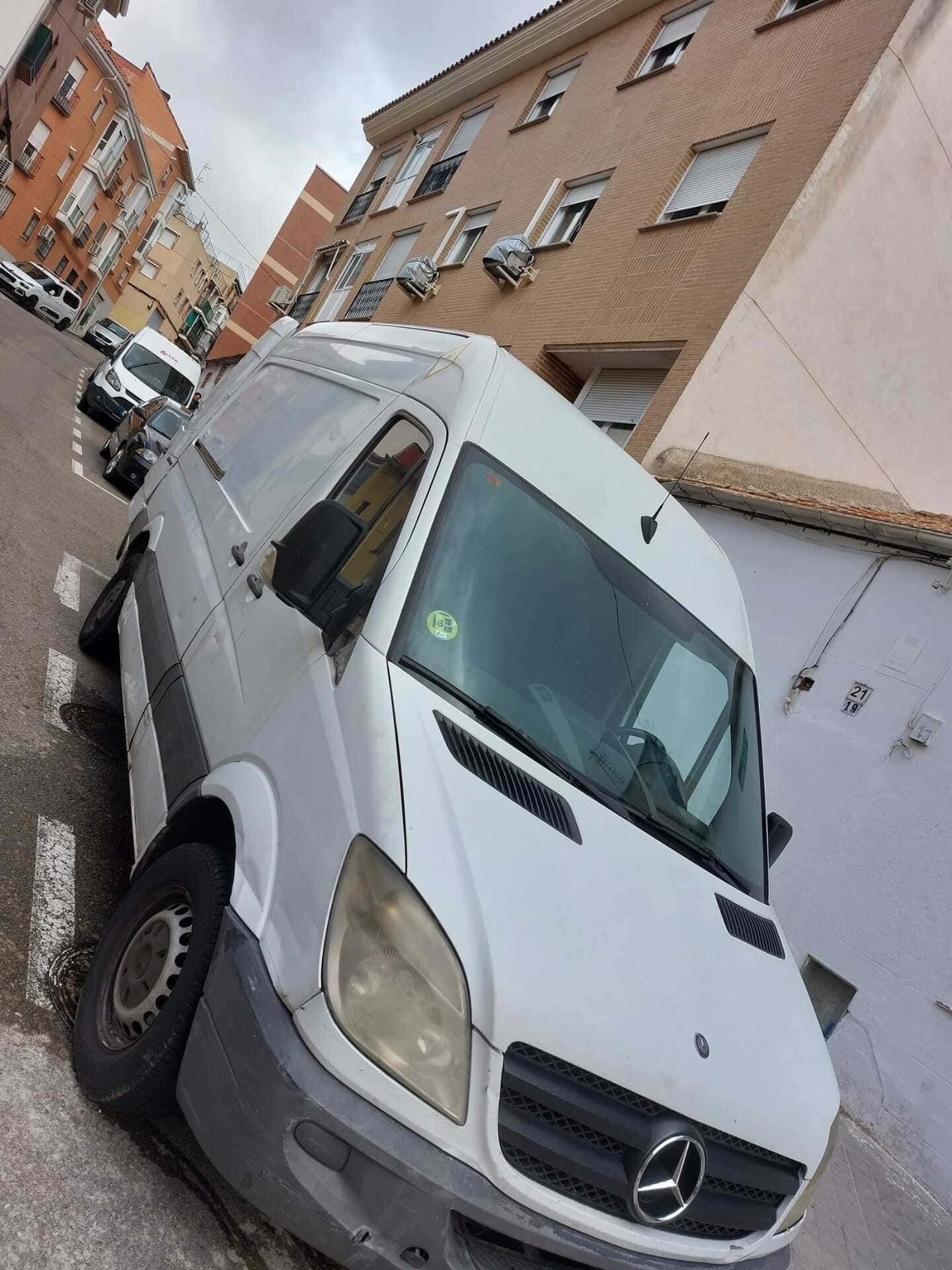 Una camioneta blanca está estacionada al costado de la carretera frente a un edificio.