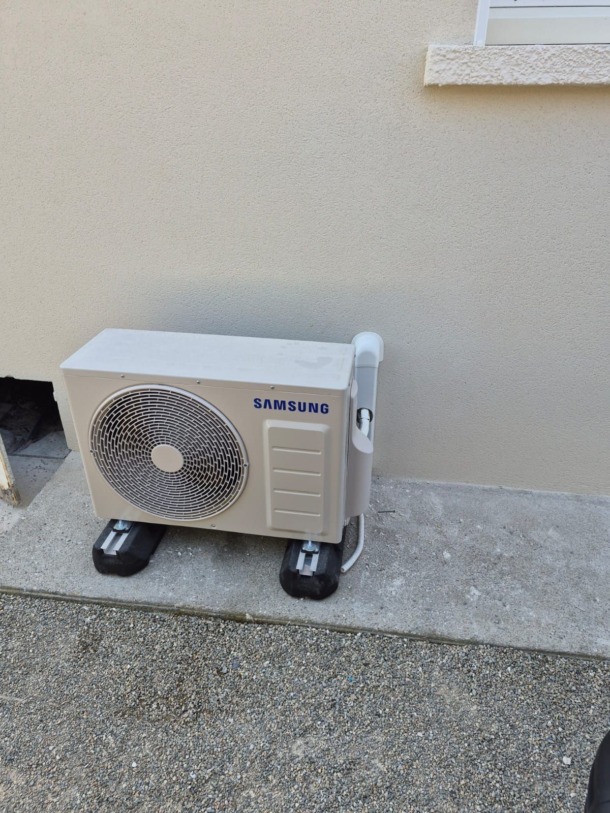 Unité de climatisation portable sur une terrasse en béton, à côté d'un mur.