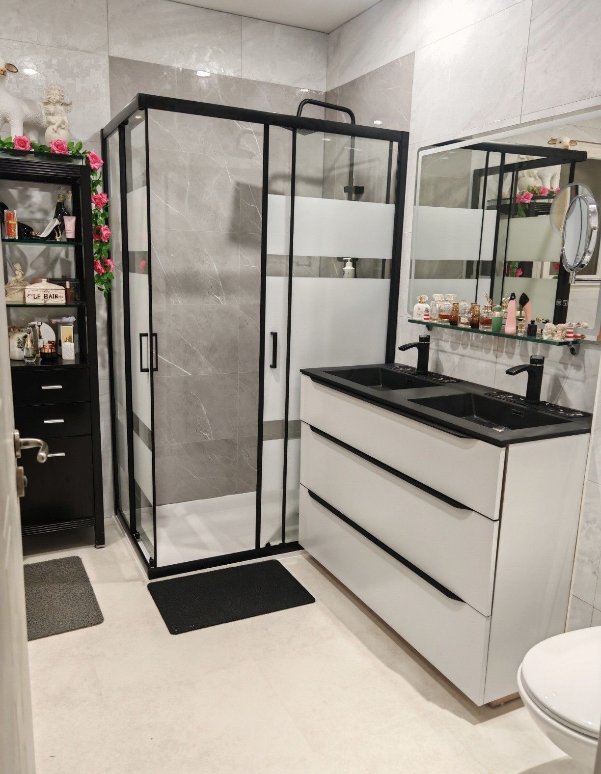 Salle de bains moderne avec douche en verre à cadre noir, meuble-lavabo blanc et grand miroir