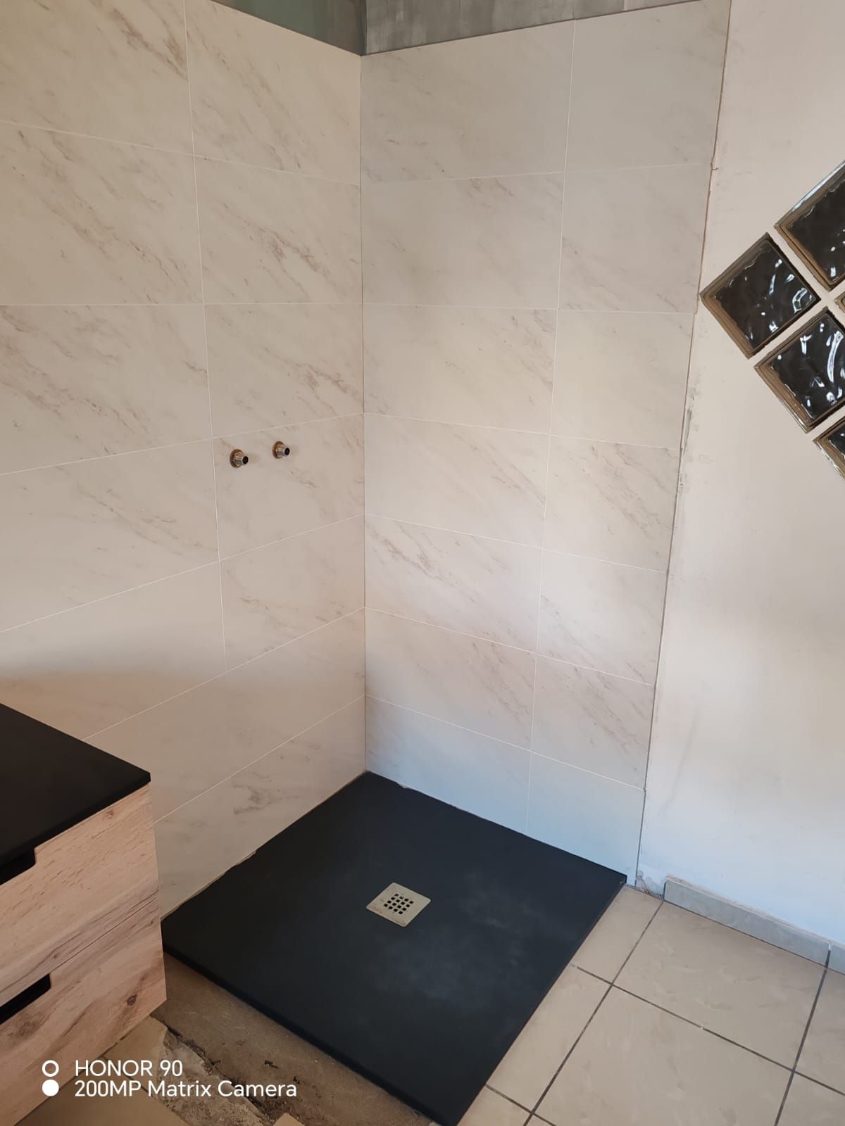 Coin de douche carrelé vide avec receveur de douche noir et bonde murale
