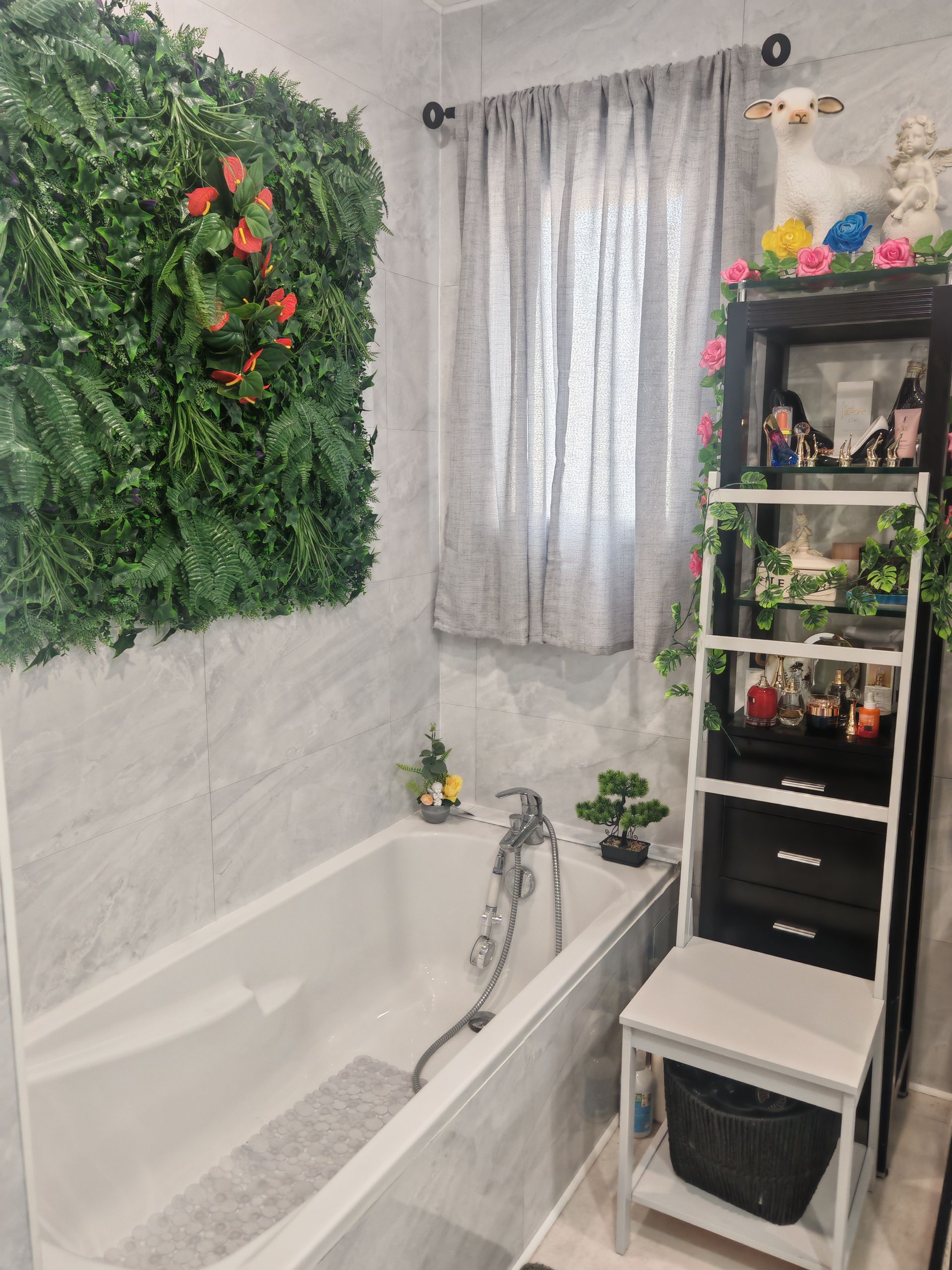 Petite salle de bains avec baignoire, décoration murale végétale, fenêtre et étagère avec plantes et jouets.