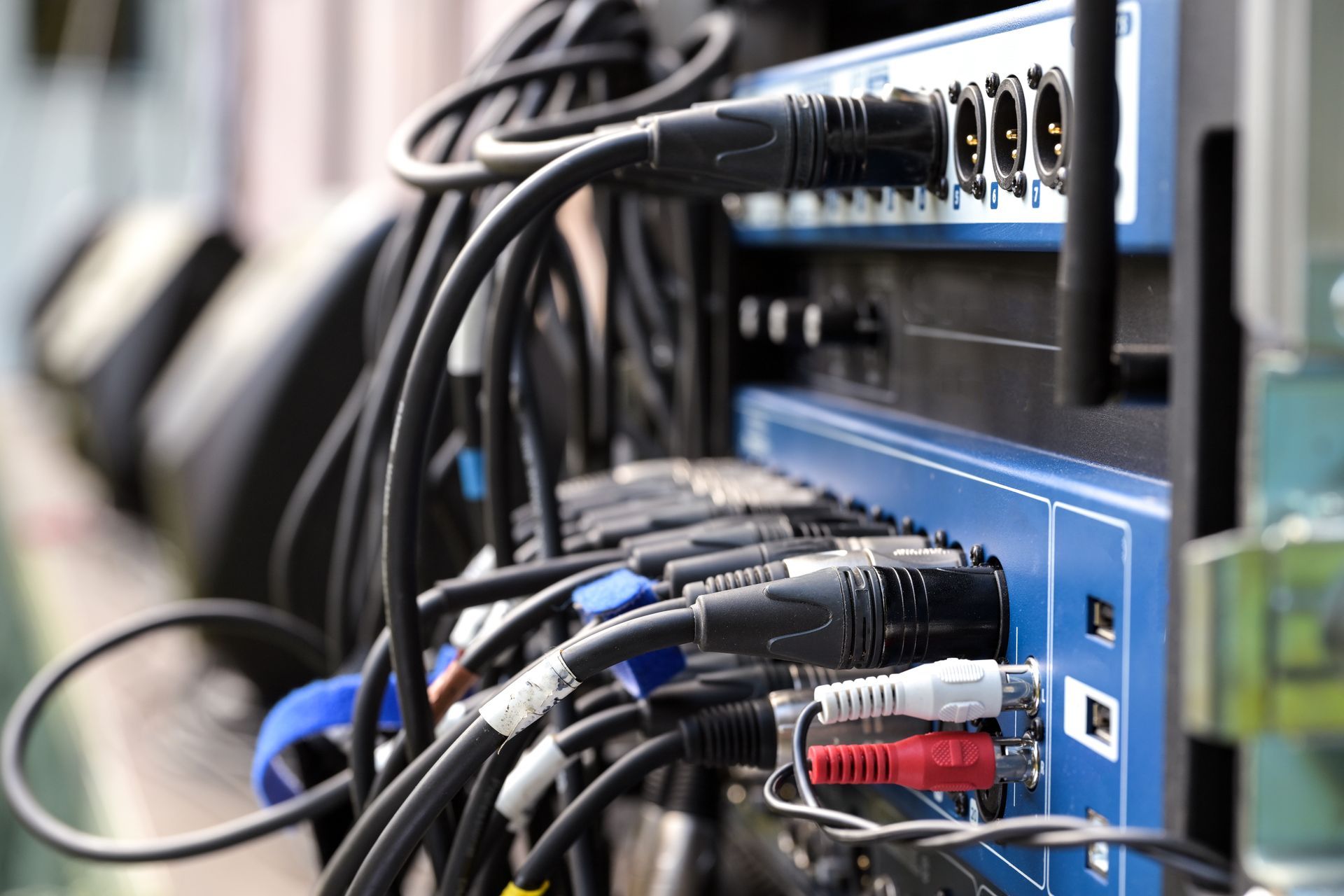 Gros plan sur un rack d'équipement audio avec de nombreux câbles noirs connectés.