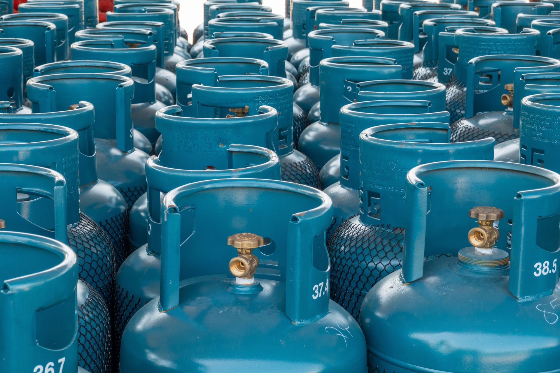 Un grand groupe de bouteilles de gaz propane métalliques turquoise, disposées en rangées bien ordonnées.