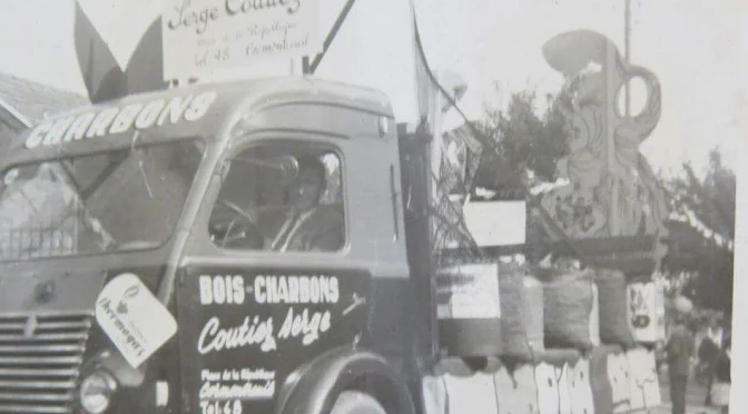 Un camion ancien portant l'inscription « Bois-Charbons Coutier Serge » participe à un défilé, transportant des décorations.