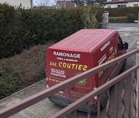 Une camionnette rouge portant l'inscription « Ramonage SAS Coutiez » est garée dans une allée résidentielle, partiellement masquée par une barrière métallique.