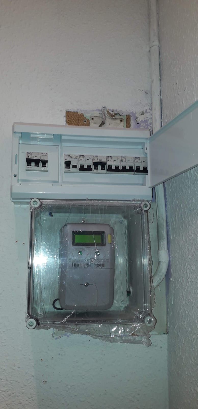 Una caja eléctrica con un medidor dentro está colgada en una pared.