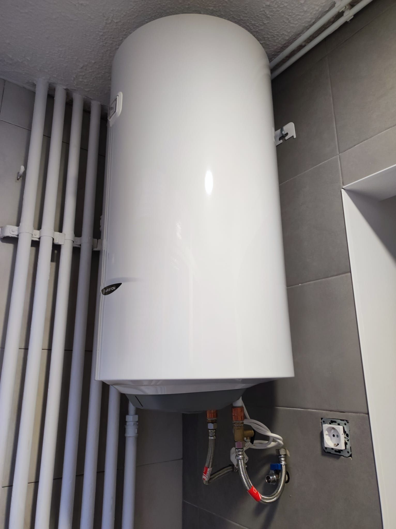 Un calentador de agua blanco cuelga del techo de un baño.