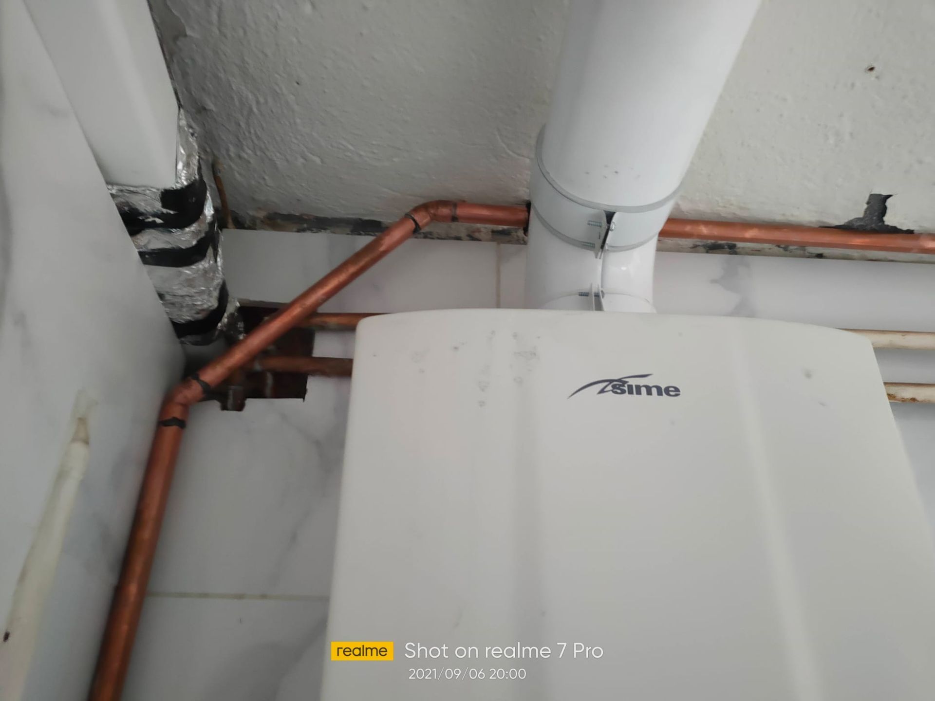 Una caldera blanca con tubos de cobre conectados a ella.