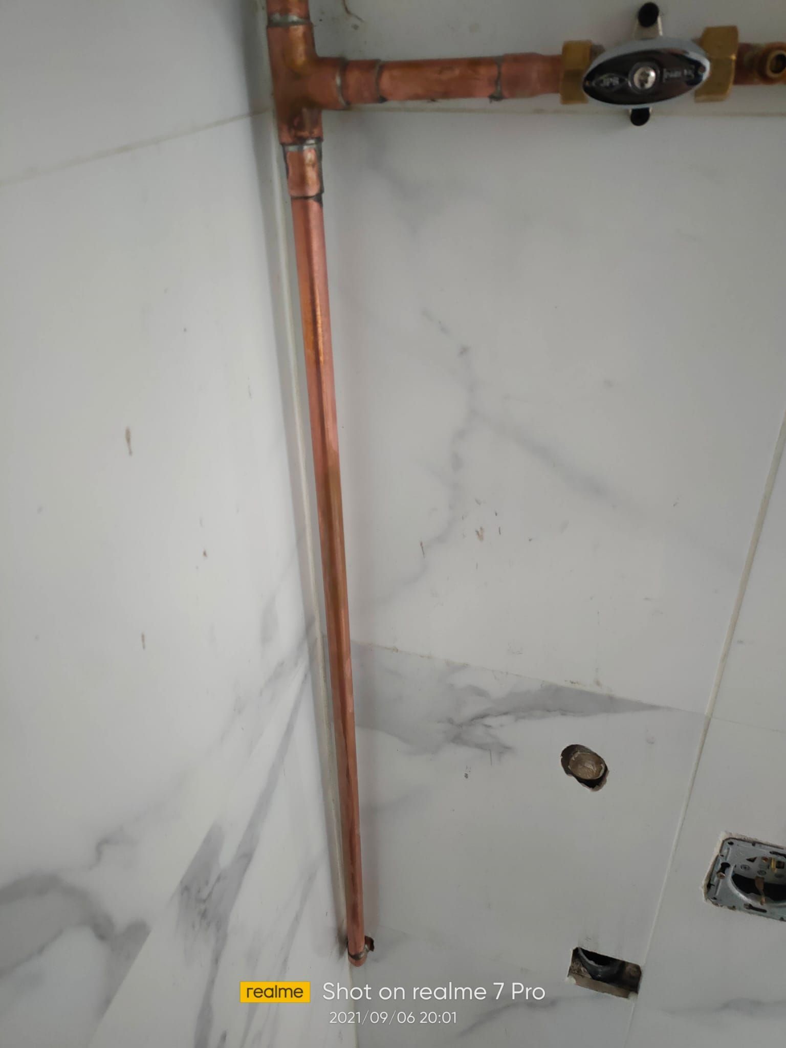 Una tubería de cobre está fijada a una pared en un baño.