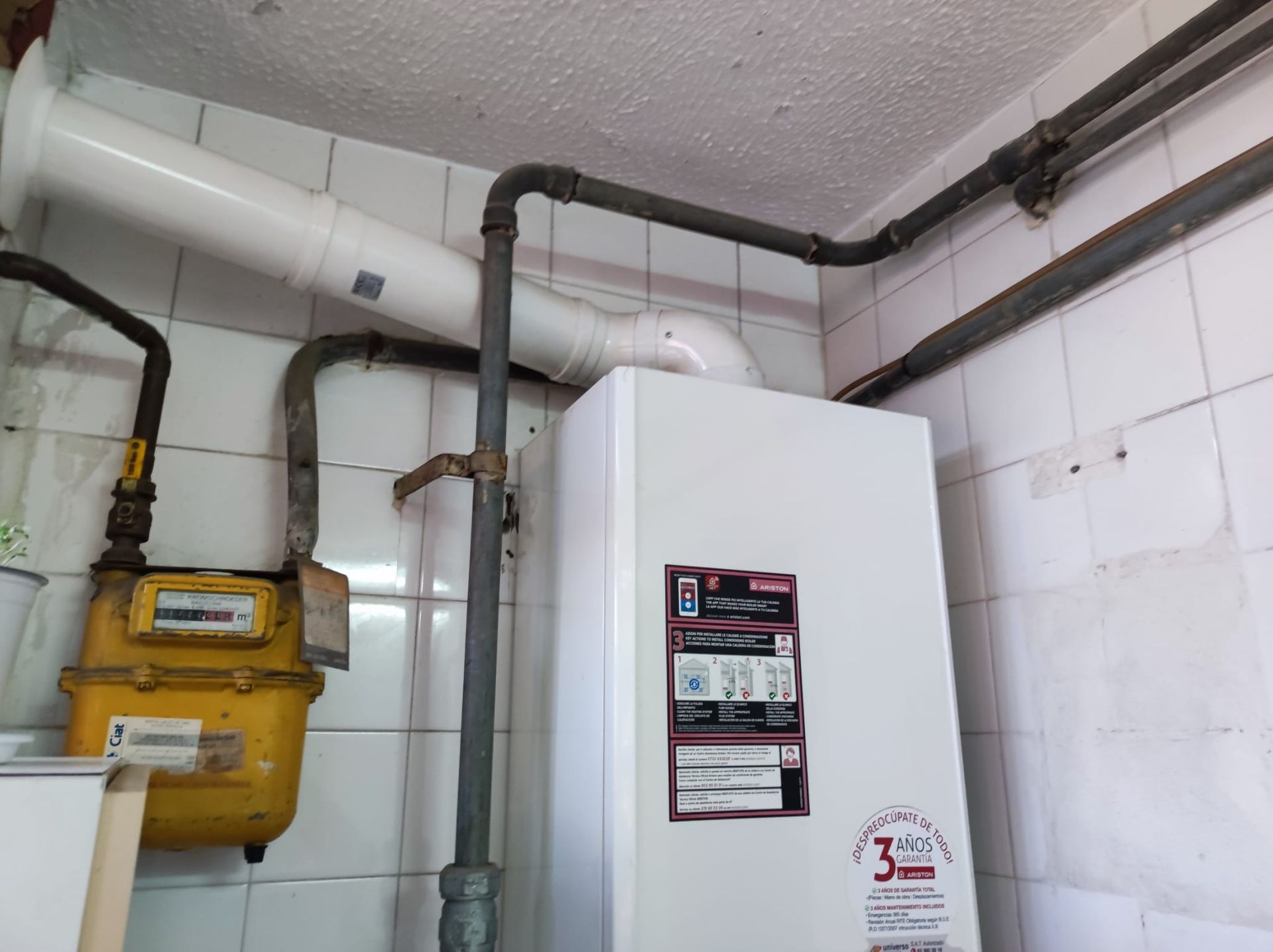 Un contador de gas está fijado a una pared al lado de una caldera.