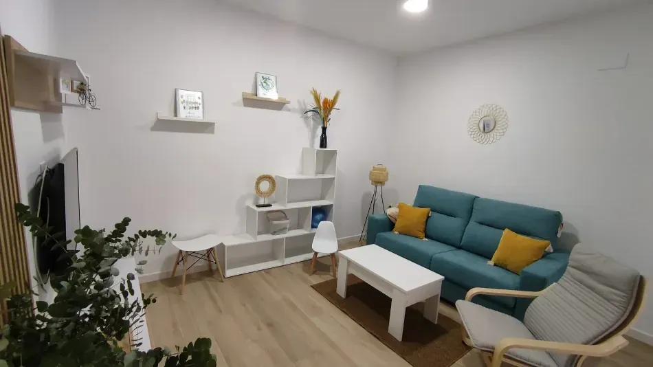 Sala de estar moderna con sofá color turquesa, mesa de centro blanca, estantes de pared y una planta en maceta.