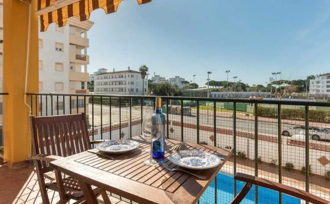 Balcón con mesa, sillas y vajilla con vistas a un hipódromo y edificios.