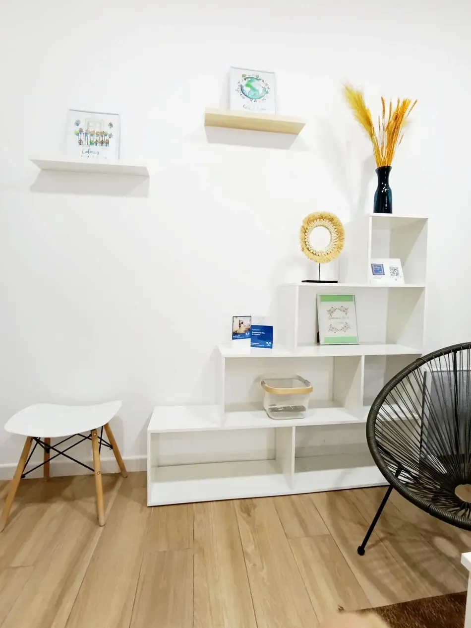 Sala de estar minimalista moderna con estantes blancos, decoración y un ventilador negro sobre un piso de madera.
