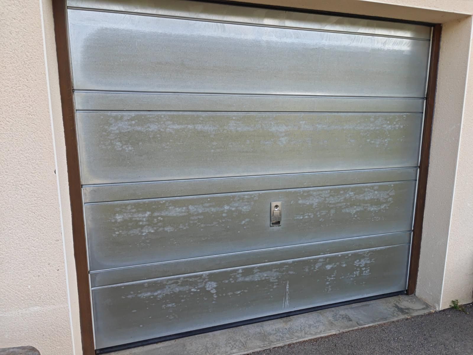 Porte de garage argentée avec garnitures, aspect vieilli.