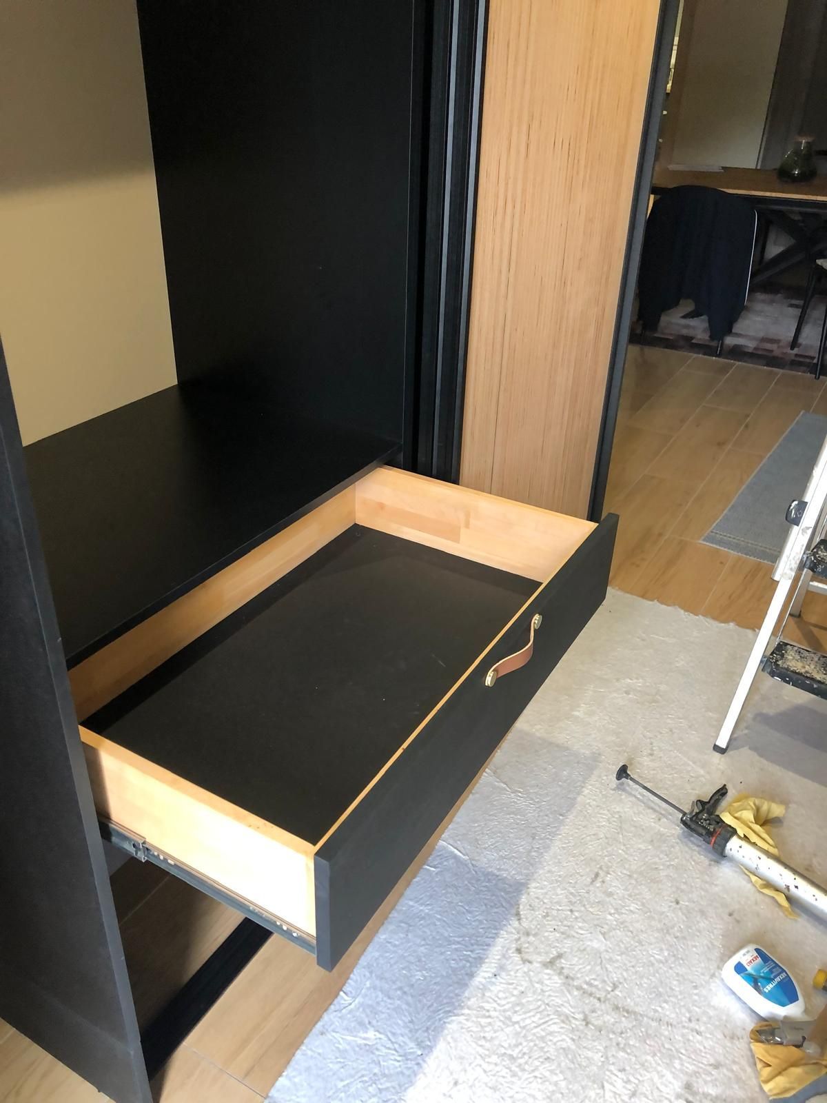 Tiroir ouvert sur un bureau. Intérieur du tiroir en bois, poignée, près du placard.