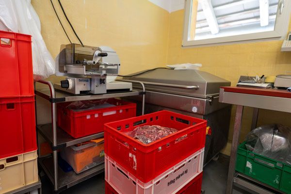 In einem Schlachthof hängen Hühner an Haken. Foto von der Kopp's Metzg AG