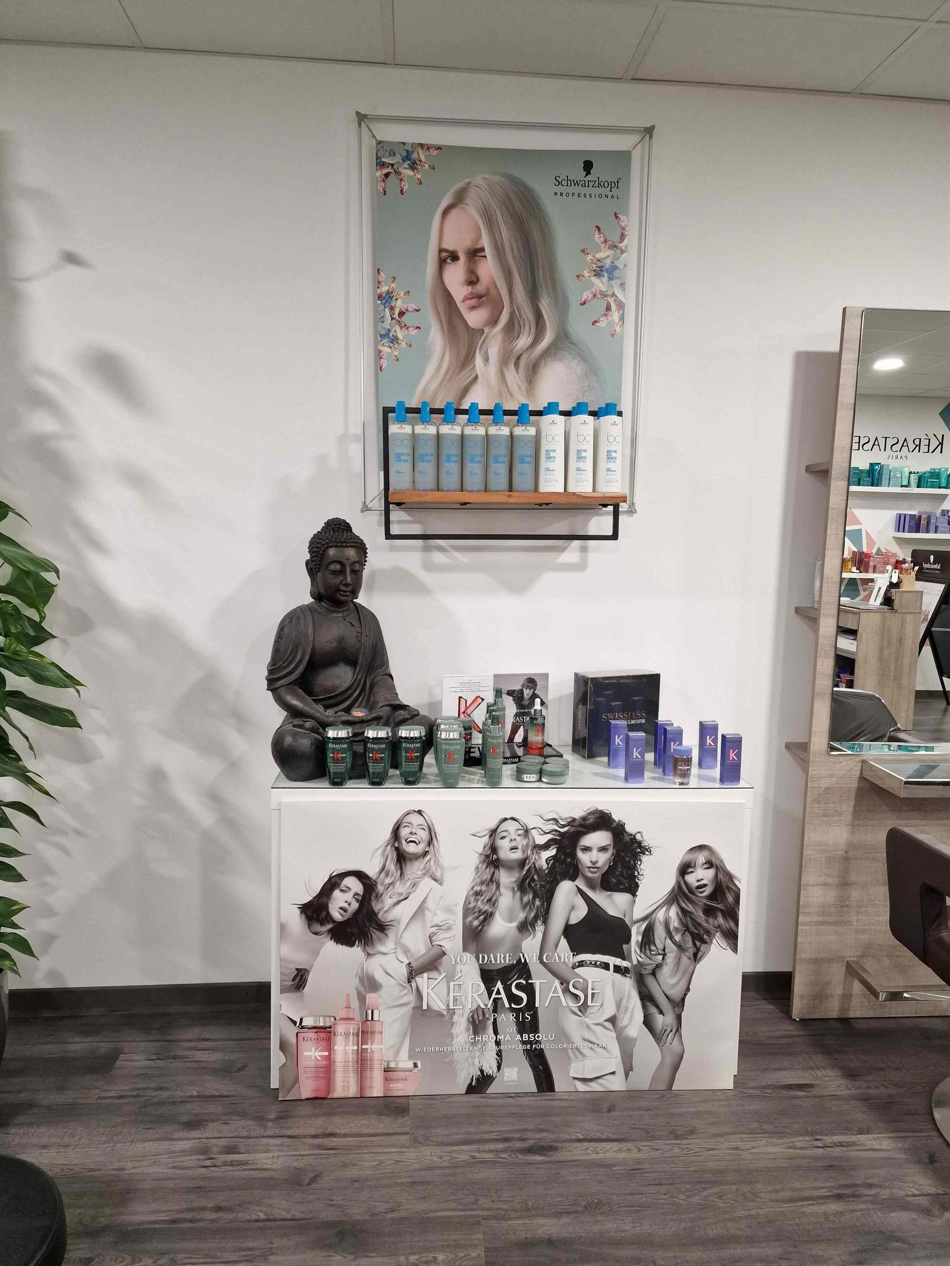 Eine Ausstellung von Haarpflegeprodukten in einem Salon mit einem Frauenbild an der Wand.