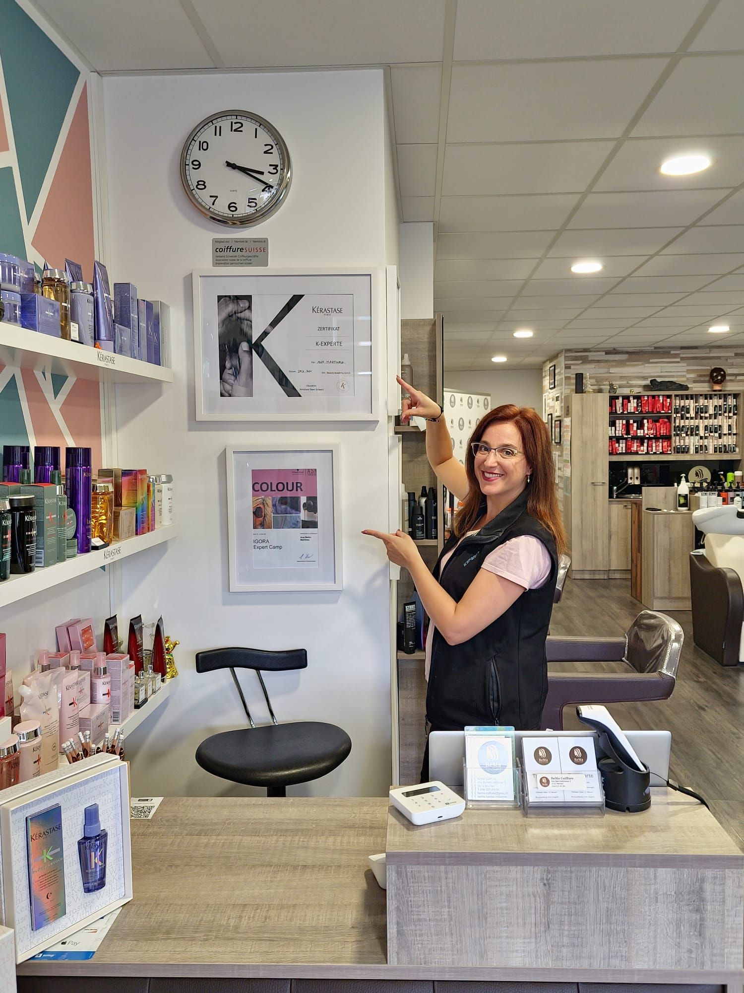 Eine Frau zeigt auf eine Uhr an der Wand in einem Salon