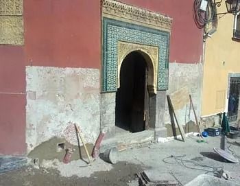 Se está remodelando un edificio rojo con un arco verde.