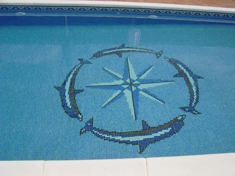 Un mosaico de delfines y una brújula en una piscina.