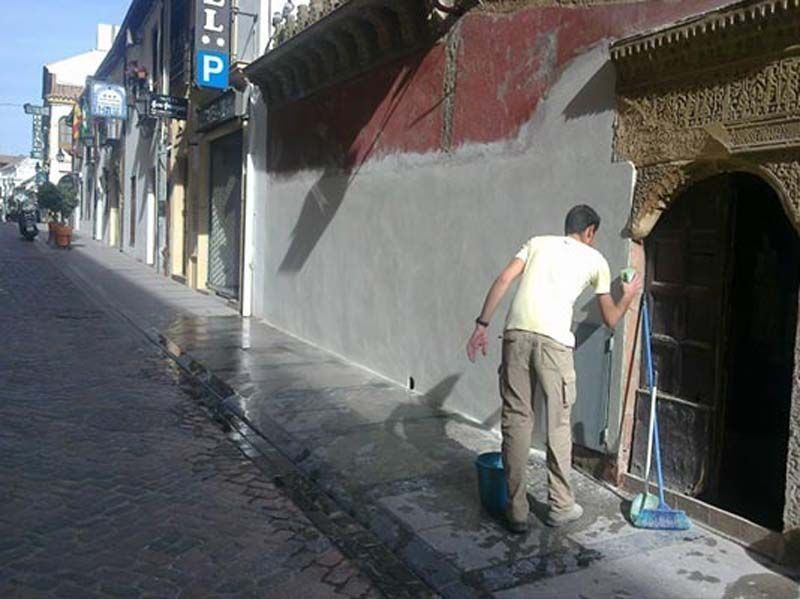 Un hombre limpiando la acera frente a un edificio con un cartel que dice hotel p