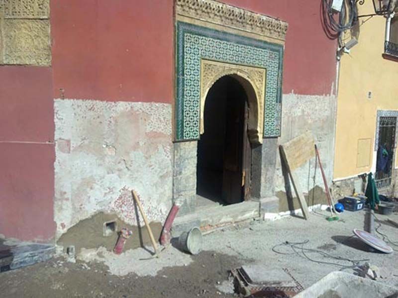 Se está remodelando un edificio rojo con un arco verde.