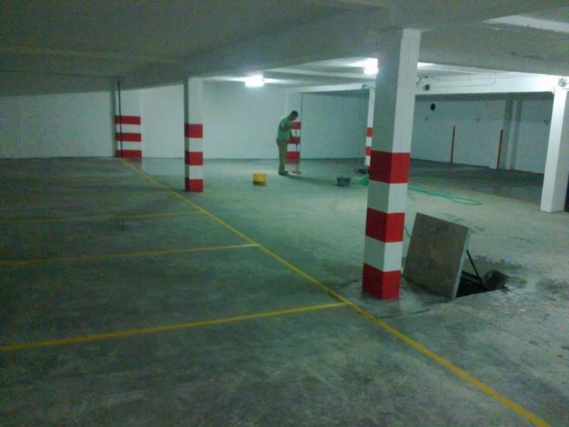 Un hombre está parado en un estacionamiento con pilares rojos y blancos.