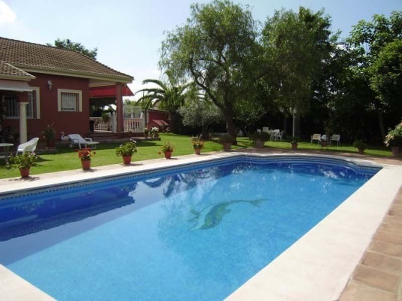 Una gran piscina con una casa al fondo.