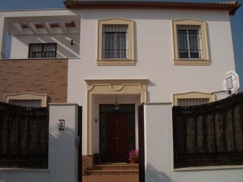 Una casa blanca con una puerta marrón y una valla negra