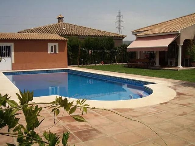Una gran piscina con una casa al fondo.