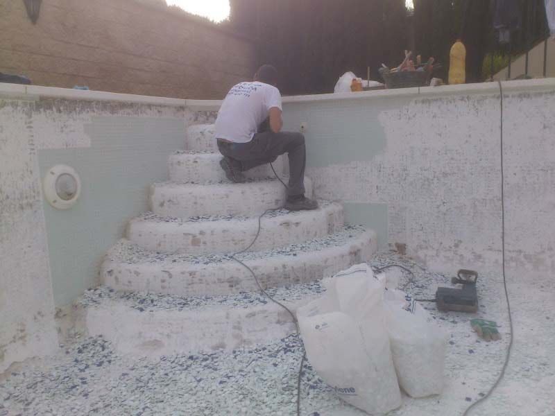 Un hombre está sentado en los escalones de una piscina.